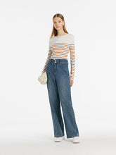 A lady wears a slim sweater and jeans.